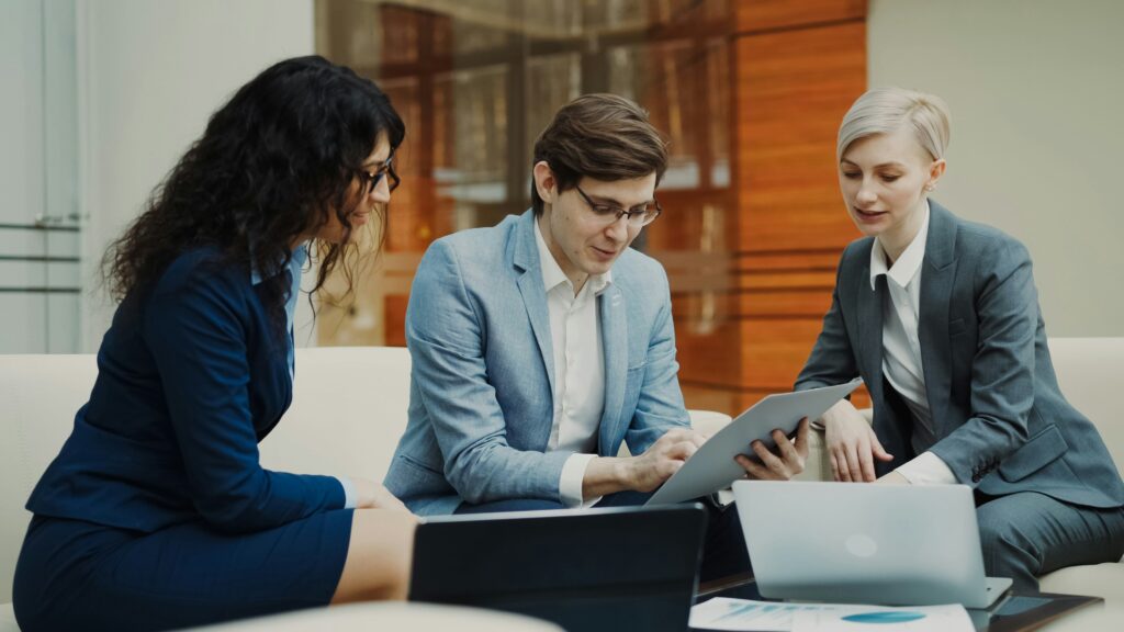 Professional discussing strategy with a colleague while working on a laptop, representing how AI debt collection software streamlines recovery and improves team efficiency.