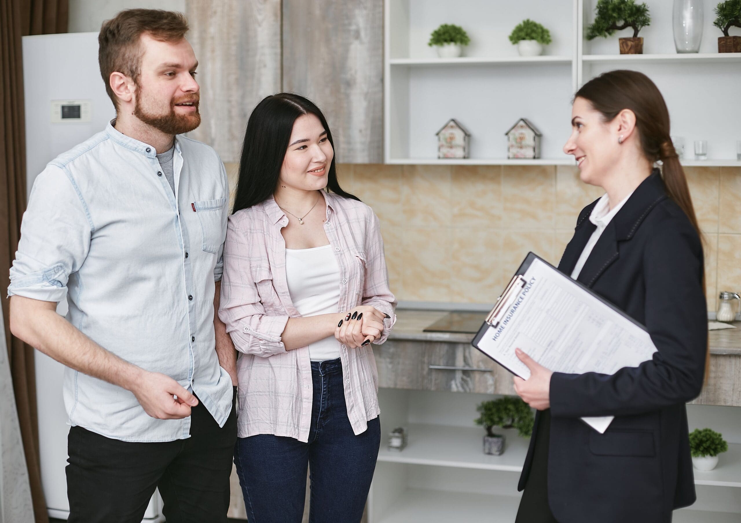 Insurance agent meeting with a couple in their kitchen to discuss a home insurance policy