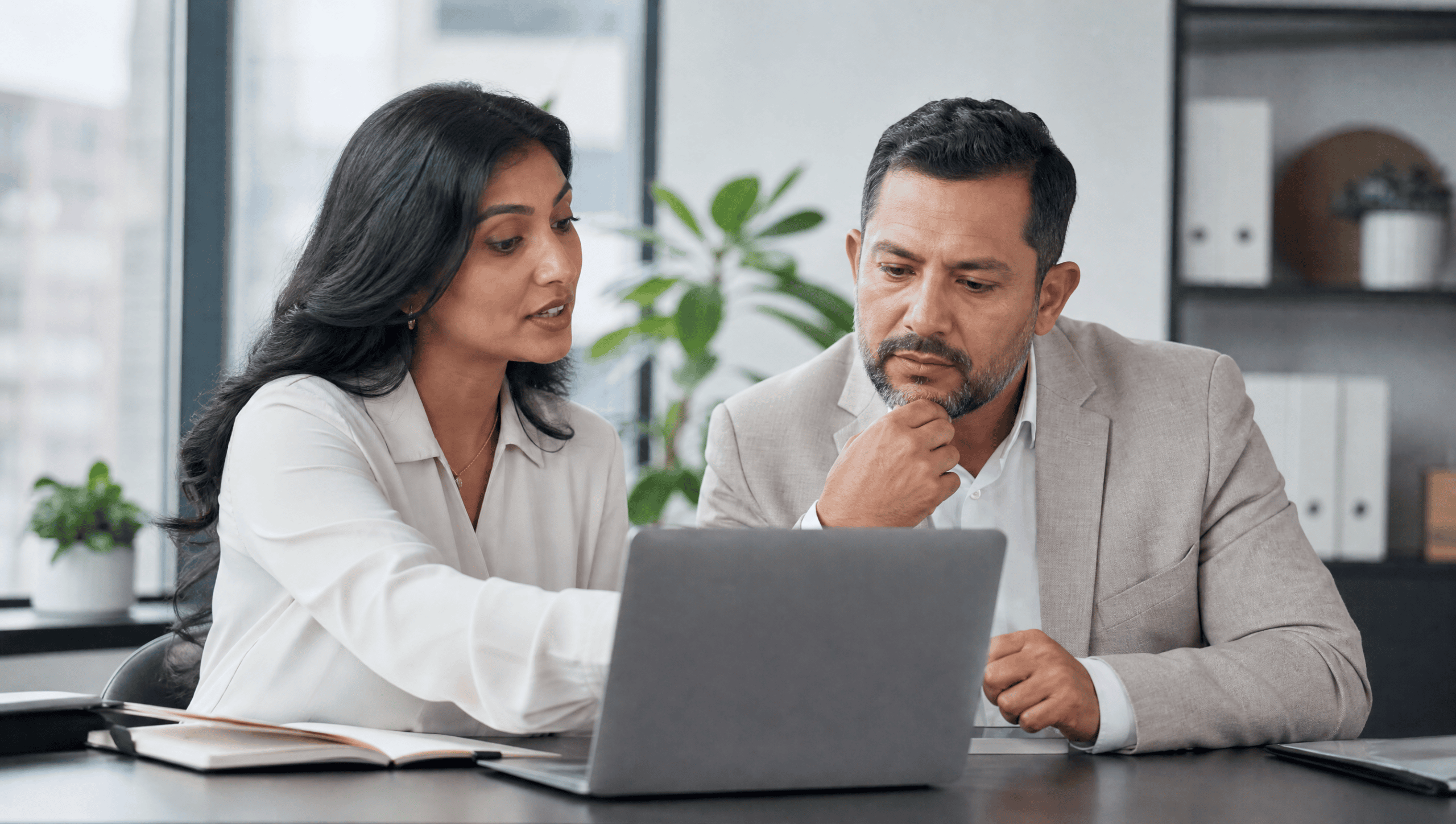 Two insurance brokers reviewing an AI lead-qualification dashboard on a laptop
