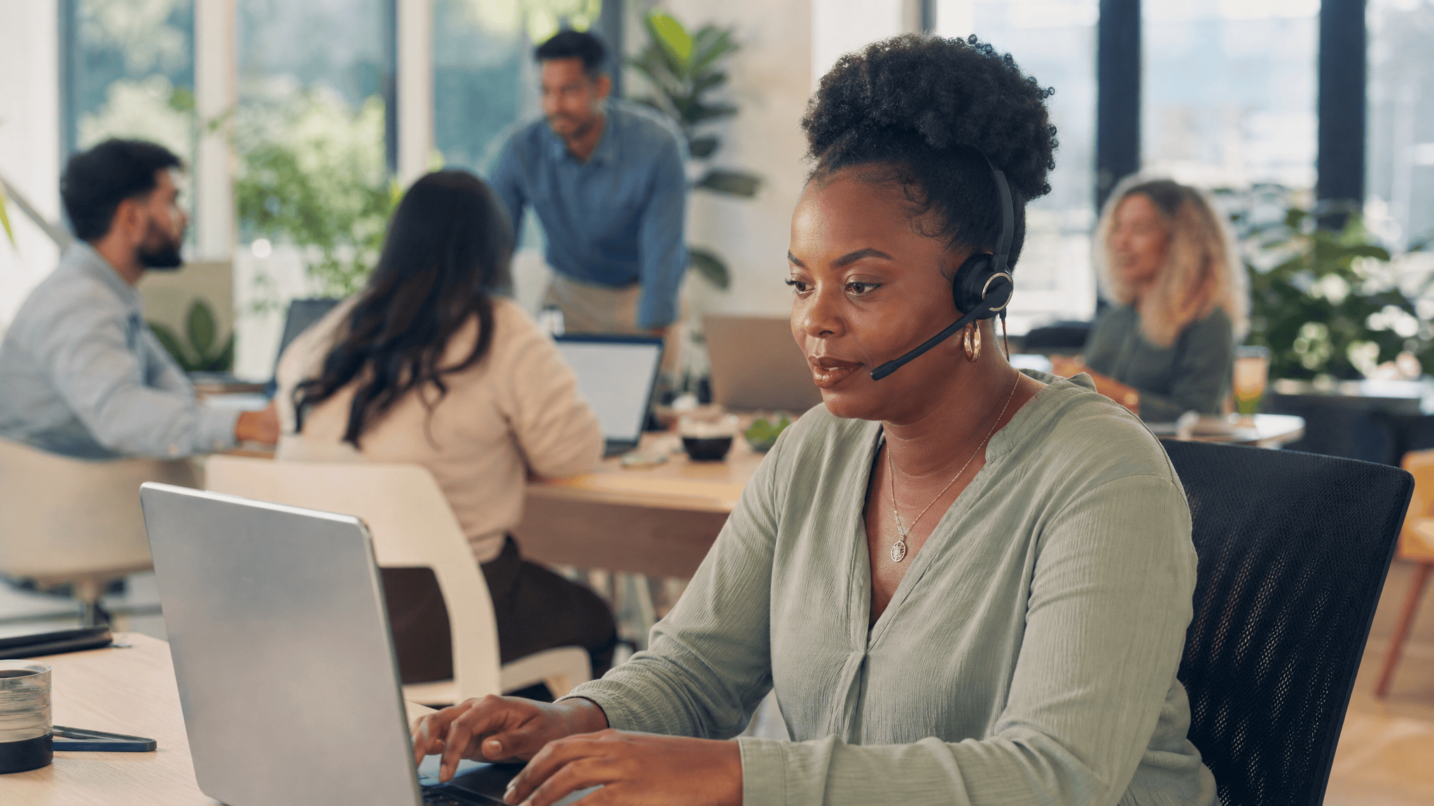 Woman with a headset working at a laptop in a bright modern office