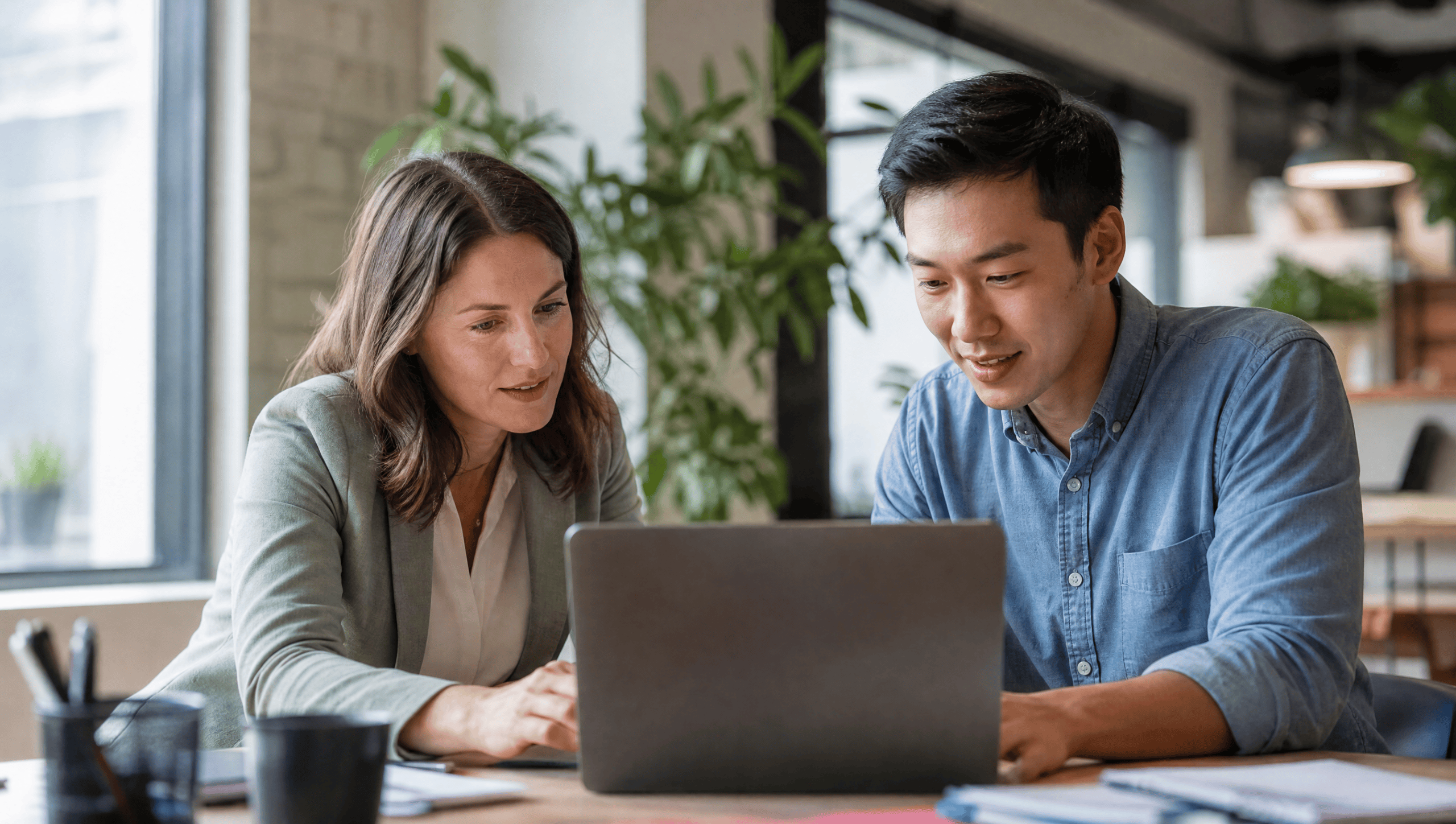 Two small-business colleagues comparing free AI form builders on a laptop