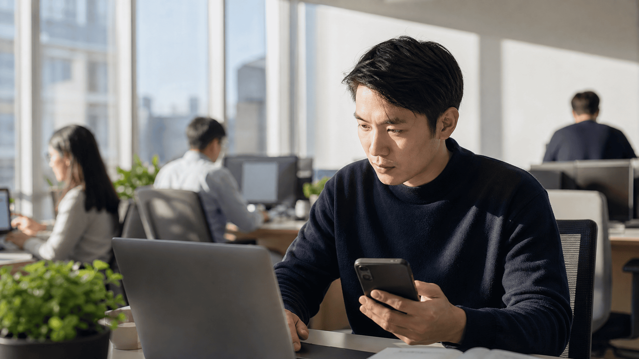 B2B marketer at a laptop with an incoming meeting notification on the phone